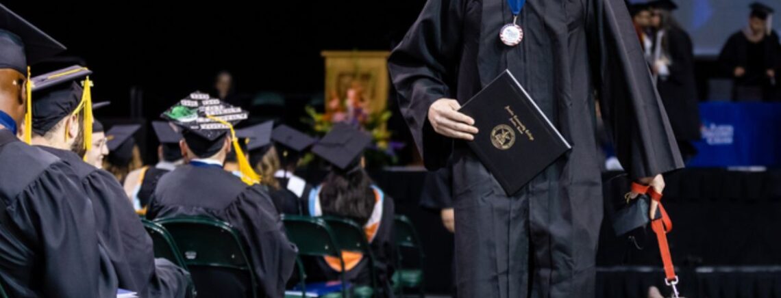 A veteran accompanied by his service dog receives his diploma from Austin Community College