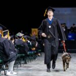 A veteran accompanied by his service dog receives his diploma from Austin Community College