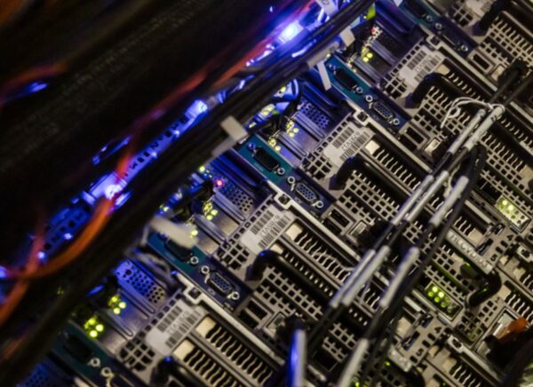A row of network servers lit with the blue glow of power lights. Cybersecurity specialists protect networks from malware, trojans, denial of service (DoS), and other attacks.