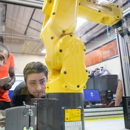 An ACC student observes a robotic arm performing work