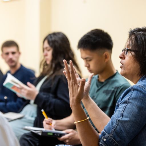 In an ACC English class, a female professor discusses literature with students, as students pay close attention and take notes.