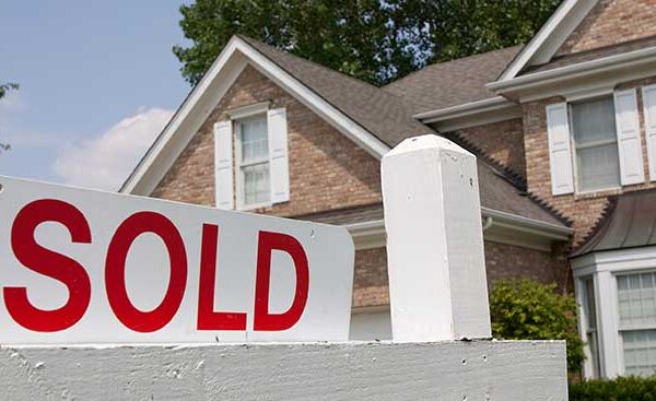 Exterior shot of a house with a sold sign out front. Close up on the word SOLD.