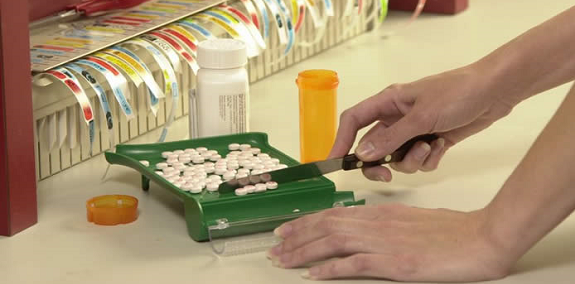 Close-up photo of pharmacy tech hands dividing pills using pill counting tray