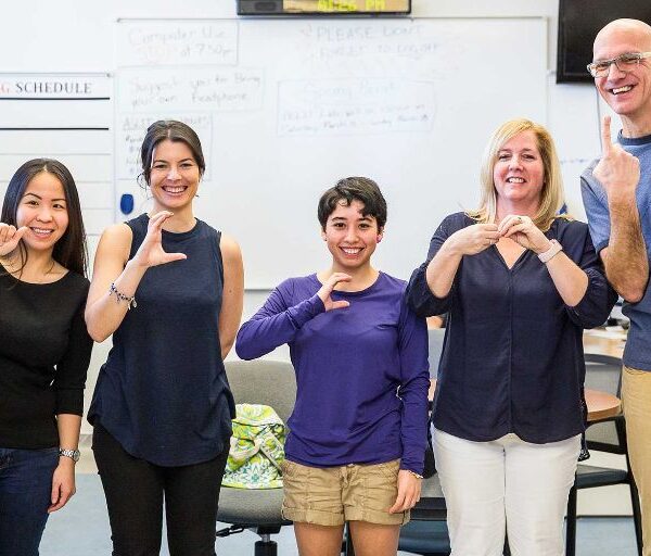 Four women and one man sign in ASL.