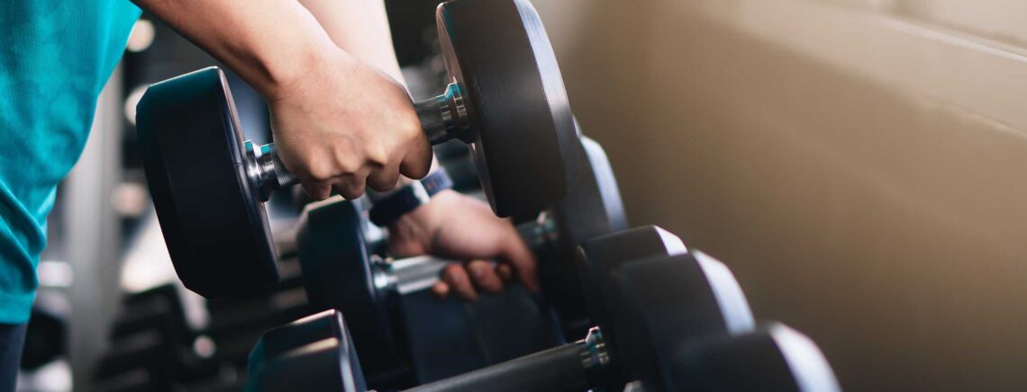 hands of man lifting dumbbells on rack in gym or fitness