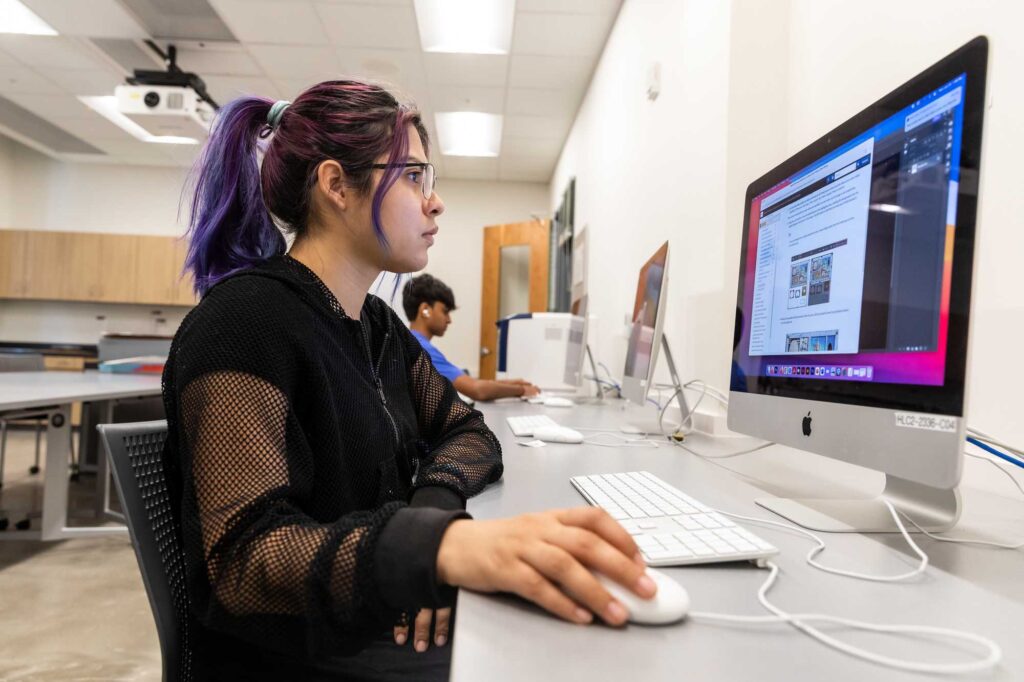 An ACC student works on a project during ACC VisComm class using a Apple computer