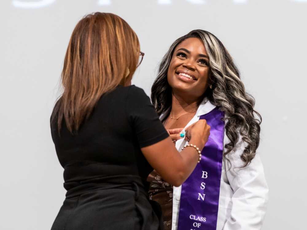 An ACC RN to BSN student smiles while receiving her pin during the pinning ceremony. 