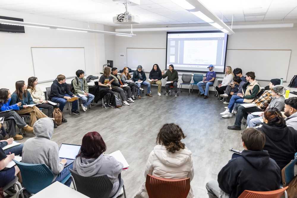 ACC students are seated in a large circle in a classroom for a class discussion. 