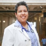 proud nursing student graduate wears a white coat and stethoscope.