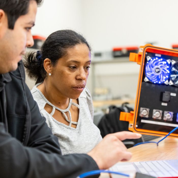 2 ACC students work on a laptop with other manufacturing equipment 