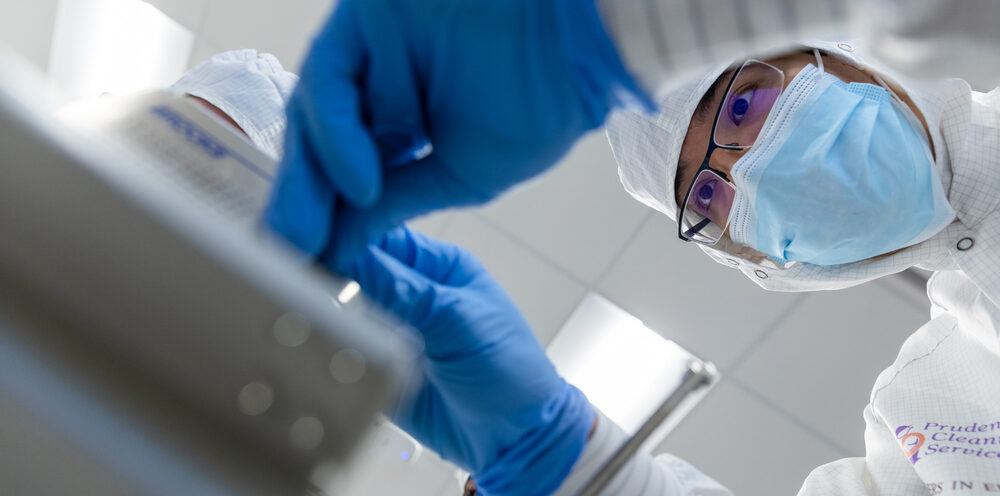 A laboratory technician in a lab coat and gloves is engaged in operating a complex machine.